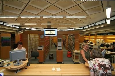 Foto: KMZ Empfangsdamen an der Theke zur Medienausgabe. Im Hintergrund sind die umfangreichen Medienbestände zu sehen