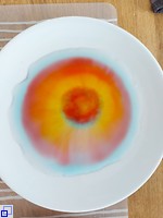 Zucker in einem Suppenteller mit Wasser und Lebensmittelfarbe bildet bunte Kringel.