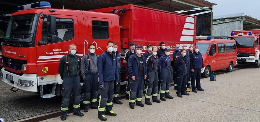 15 Männer in Einsatzkleidung stehen vor einem Feuerwehrfahrzeug.