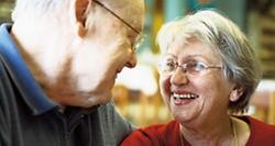 Eine ältere Frau und ein älterer Mann lachen sich gegenseitig an