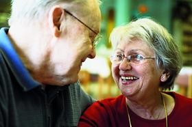 Eine ältere Frau und ein älterer Mann lächeln sich gegenseitig an