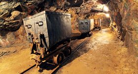 Drei alte rostige Bergbauwagen fahren auf Schienen durch ein Bergwerk 