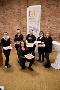 6 Landfrauen zeigen die angerichteten Speisen auf Tabletts.