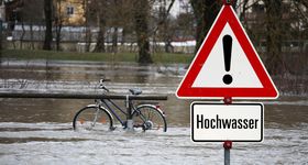 Das Hochwasser verschlingt ein Fahhrad und Bäume 